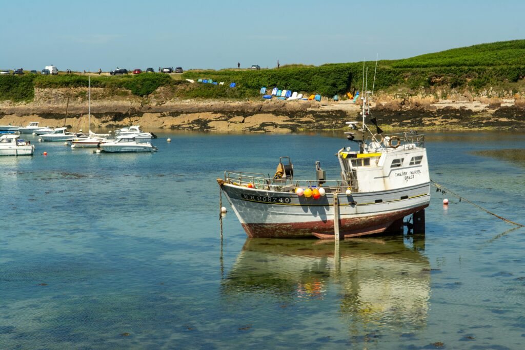 Accueil Fishing boats docked in a natural harbor during low tide, showcasing calm waters and a tranquil coastal scene.